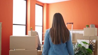 Genç, güzel, İspanyol bir kadın yeni evinde kendine gülerek duruyor.