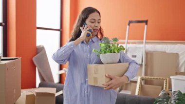 Genç ve güzel İspanyol bir kadın telefonda konuşuyor. Elinde yeni evinde bir kutu var.