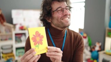 Young hispanic man preschool teacher having vocabulary lesson at kindergarten