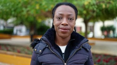 Afro-Amerikalı kadın parkta kendinden emin bir şekilde gülümsüyor.