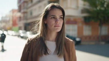 Sokakta duran, ciddi ifadeli, beyaz bir kadın.