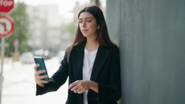 Genç İspanyol kız gülümsüyor. Kendine güveni tam. Sokakta akıllı telefonun yanında özçekim yapıyor.