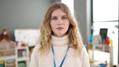 Young blonde woman preschool teacher smiling confident standing at kindergarten