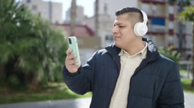 Genç İspanyol adam parkta müzik dinliyor ve dans ediyor.