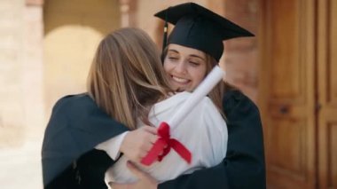 Two women mother and graduated daughter standing together at campus university