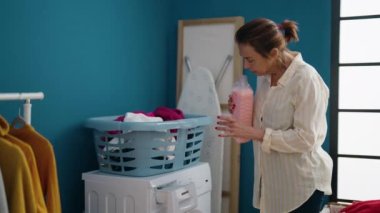 Çamaşır odasında deterjan dolduran orta yaşlı bir kadın.