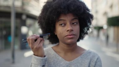 Afro-Amerikalı kadın gülümsüyor. Caddedeki akıllı telefondan kendine güvenen sesli mesaj dinliyor.