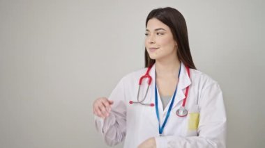Genç, güzel İspanyol kadın doktor gülümsüyor. Kendinden emin, izole beyaz arka planda elleri yana bakıyor.