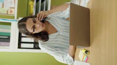 Young african american woman business worker using laptop talking on smartphone at office