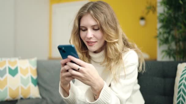 Ung Blond Kvinna Med Smartphone Sitter Soffan Hemma — Stockvideo