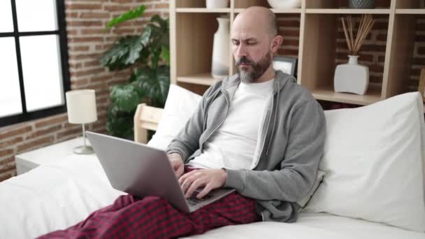 Ung Skallig Man Med Laptop Sitter Sängen Sovrummet — Stockvideo