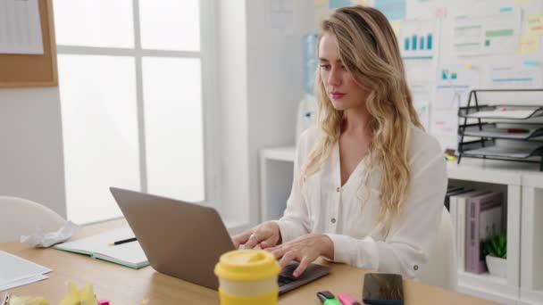 Νεαρή Ξανθιά Εργαζόμενη Στις Επιχειρήσεις Χρησιμοποιώντας Laptop Γράφοντας Στο Σημειωματάριο — Αρχείο Βίντεο