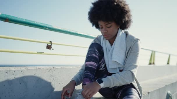 African American Woman Tying Shoe Sitting Bench Seaside — Stock Video