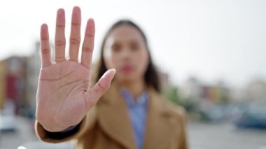 Genç, güzel, İspanyol bir kadın sokakta el hareketlerini durduruyor.