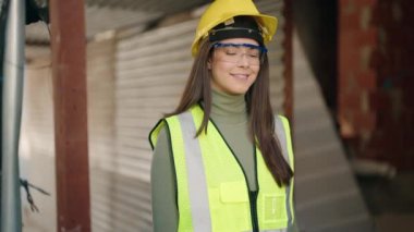 Young hispanic woman architect standing with arms crossed gesture at construction site
