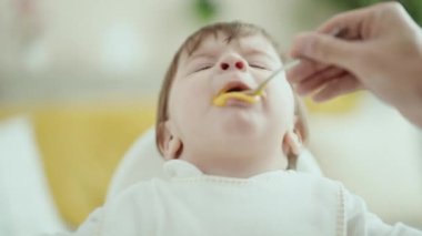 Sevimli İspanyol bebek sandalyeye oturmuş, evde yemek yiyor.