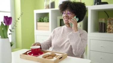 Genç Afrikalı Amerikalı kadın kahvaltısını evde akıllı telefondan yapıyor.