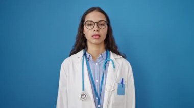Genç, güzel İspanyol kadın doktor el ele yemin ediyor. Mavi arka plan üzerinde.