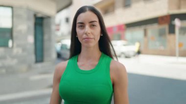 Genç ve güzel İspanyol kadın gülümsüyor. Kendine güveniyor. Sokakta elleriyle fotoğraf jesti yapıyor.