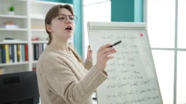 Young blonde woman teacher explaining maths lesson at library university