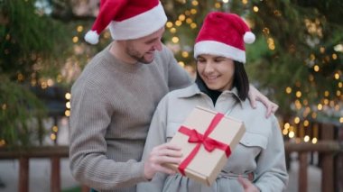 Park 'ta hediye getiren, Noel şapkalı genç bir çift.