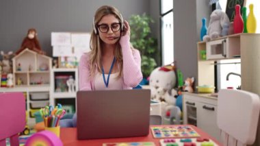 Genç sarışın kadın öğretmen anaokulunda video görüşmesi yapıyor.