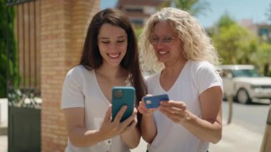 İki kadın anne-kız akıllı telefon ve kredi kartı kullanıyor.
