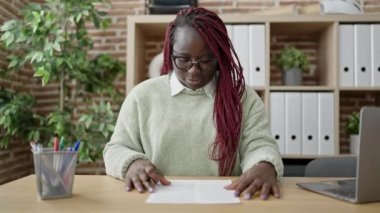 Örgülü saçlı Afrikalı kadın ofiste bir belge imzalıyor.