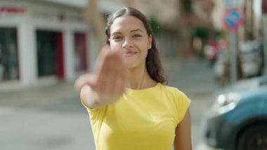 Genç Afro-Amerikan kadın gülümsüyor kendinden emin bir şekilde sokakta el kol hareketi yapıyor.
