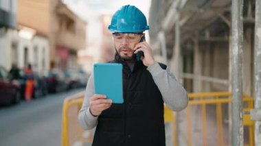Young latin man worker with serious expression talking on the smartphone at street