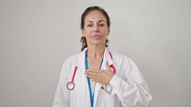 中年惊慌失措的女医生在孤独的白色背景下双手托起胸膛宣誓 — 图库视频影像