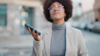 Afro-Amerikalı kadın gülümsüyor. Akıllı telefondan konuşuyor.