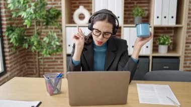 Genç, güzel İspanyol iş kadını. Dizüstü bilgisayar kullanıyor. Ofiste dans ediyor.