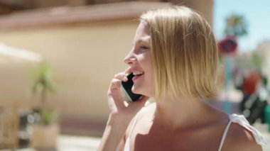 Sokakta akıllı telefon kullanan, kendine güvenen genç sarışın kadın.