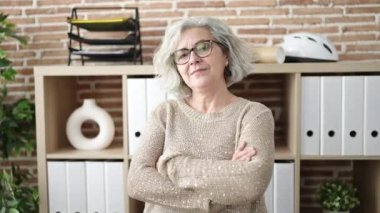 Middle age woman with grey hair business worker smiling confident standing with arms crossed gesture at office