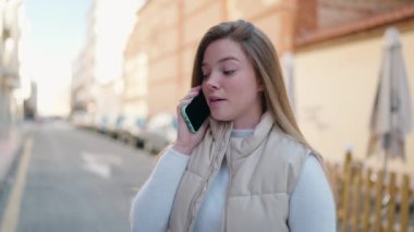 Genç sarışın kadın gülümsüyor. Kendine güveni tam. Akıllı telefondan konuşuyor.
