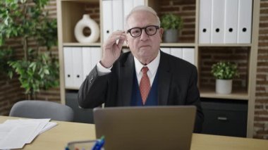 kıdemli iş adamı ofiste dizüstü bilgisayarla çalışmaktan yoruldu