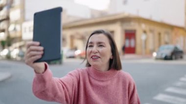 Middle age woman smiling confident having video call at street