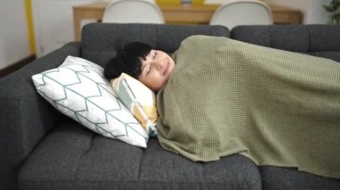 Young chinese woman lying on sofa sleeping at home