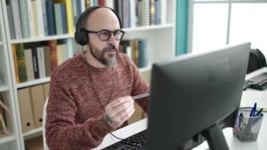 Genç, kel, gülümseyen bir öğrenci üniversite sınıfında kendine güvenen bir video görüşmesi yapıyor.