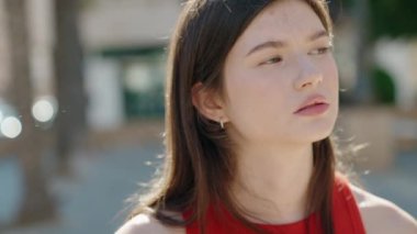 Young caucasian woman standing with serious expression at park