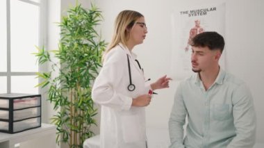 Genç çift doktor ve hasta, klinikte otoskop kullanarak kulak dikiyorlar.