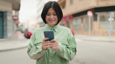 Sokakta akıllı telefon kullanan, kendine güvenen genç Çinli bir kadın.
