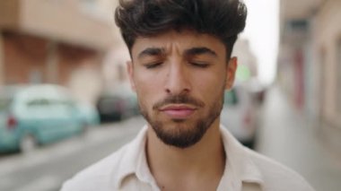 Genç Arap adam sokakta kendine güvenerek gülümsüyor.