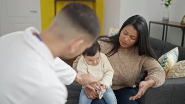 Klinikte bebek sıcaklığını ölçen çift ve oğul.