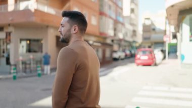 Genç İspanyol adam gülümsüyor. Kendine güveni tam. Sokakta çapraz hareketlerle duruyor.