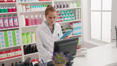 Genç ve güzel İspanyol kadın eczacı eczanede bilgisayar ve dokunmatik bir ifade kullanıyor.