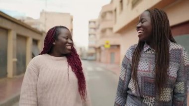 Two african american women smiling confident speaking at street