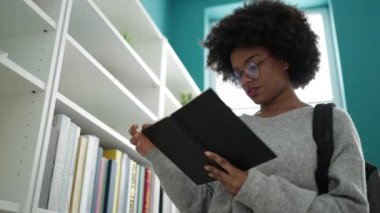 Kütüphane Üniversitesinde kitap okuyan Afrikalı Amerikalı kadın öğrenci