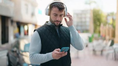 Sokakta müzik dinlerken kendinden emin gülümseyen İspanyol genç adam.